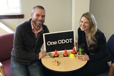 Two employees holding a sign that reads "One ODOT"