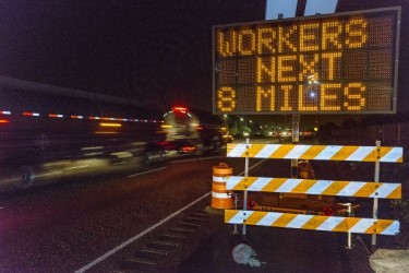 Roadside safety sign that reads, "workers next 8 miles."