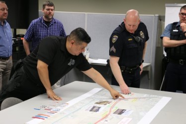 An employee and a police officer discuss and pointing at a map.