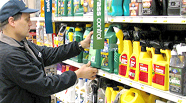 Man inspecting a fertilizer bottle on a shelf. 