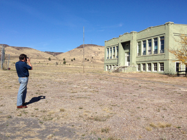Man taking a photof of an abandoned building in the High Desert.